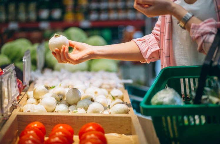 Armadilhas luminosas em supermercados: mulher escolhendo verduras no supermercado.